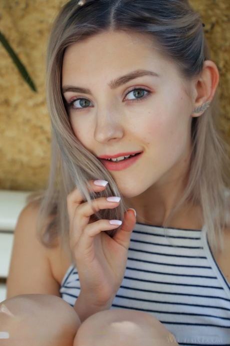 Миниатюрная молоденькая Ева Элфи держит цветок, позируя обнаженной на скамейке во внутреннем дворике картинка 3