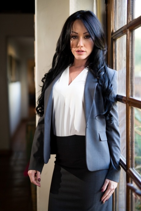 Темноволосая женщина снимает блейзер и юбку, чтобы позировать обнаженной перед окном картинка 1