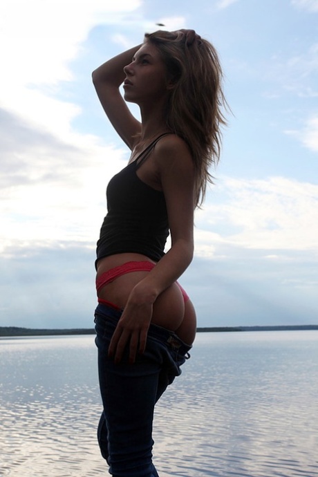 Девушка по соседству Меган показывает свои сиськи, сидя на камне в озере картинка 6