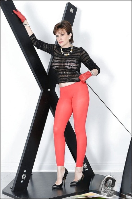 Сексуальная зрелая красотка с большими сиськами и горячей попкой позирует в красных колготках картинка 1