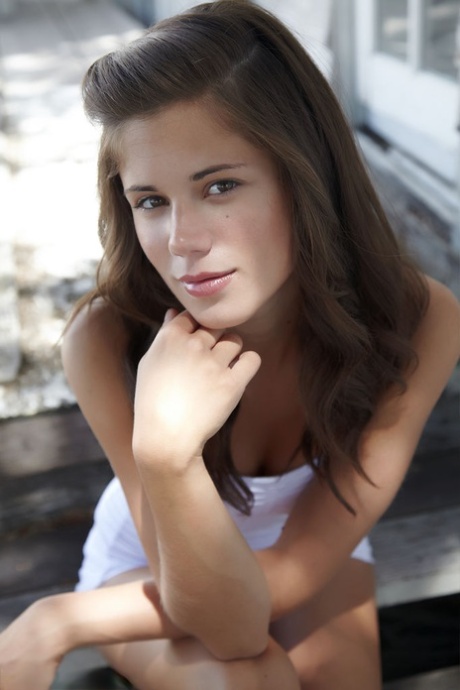 Симпатичная молоденькая малышка Каприс показывает свои маленькие сиськи и лысую киску возле коттеджа картинка 1