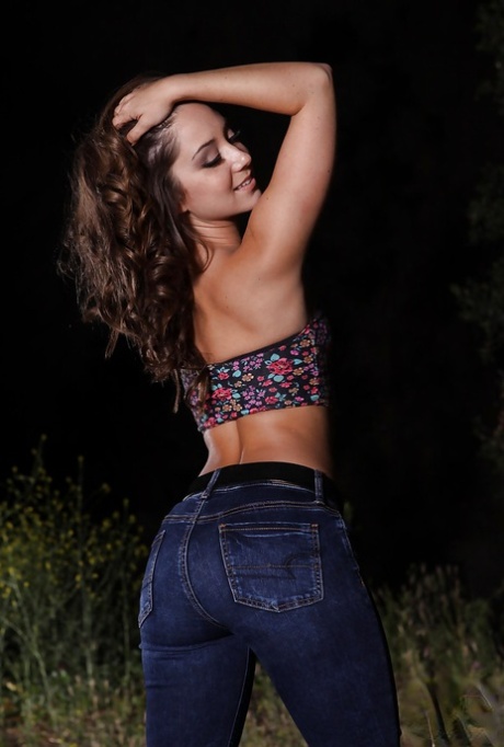 Улыбчивая девушка в синих джинсах раздевается и обнажает свои изящные изгибы на открытом воздухе картинка 3