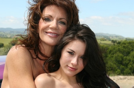 Зрелая леди и пара девушек помоложе позируют топлесс на машине в поле картинка 1